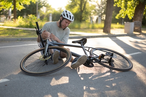 Injured cyclist sitting on the ground after a crash — Millington bicycle accident lawyer providing legal help for injured riders. Contact Mogy Law TN to start your Millington bicycle accident case today.