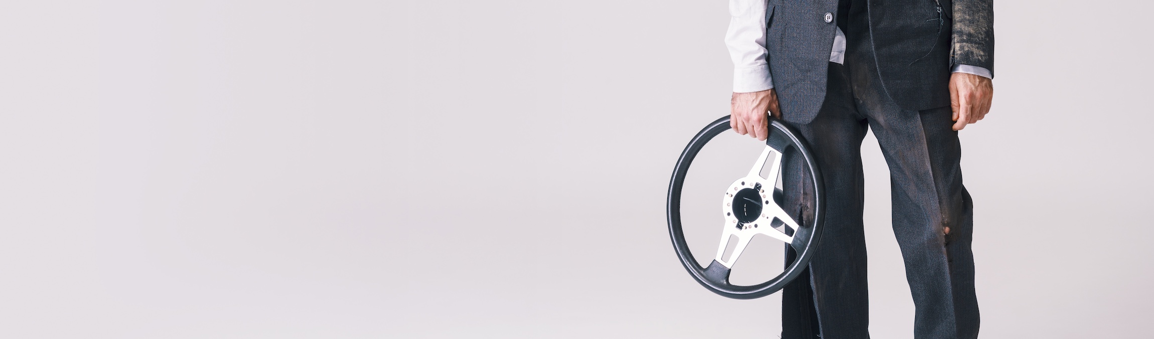 An injured man in a gray suit and white shirt, holding a black steering wheel, representing a nearby injury lawyer offering legal consultation services.