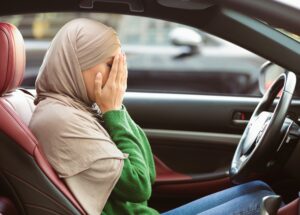 A distressed woman is sitting in a car covering her face with her hands and is experiencing shock after a car accident in Tennessee.