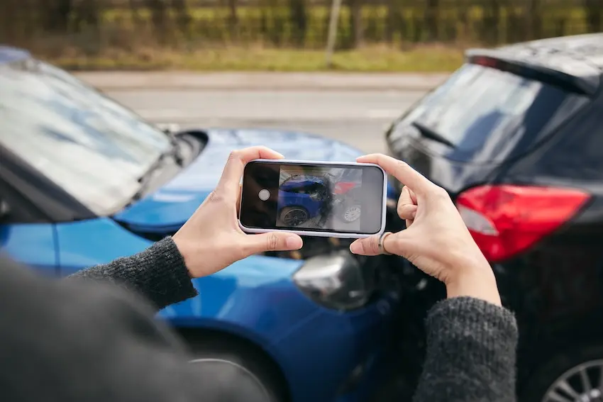 Nashville car accident victim documenting vehicle damage with phone at crash scene